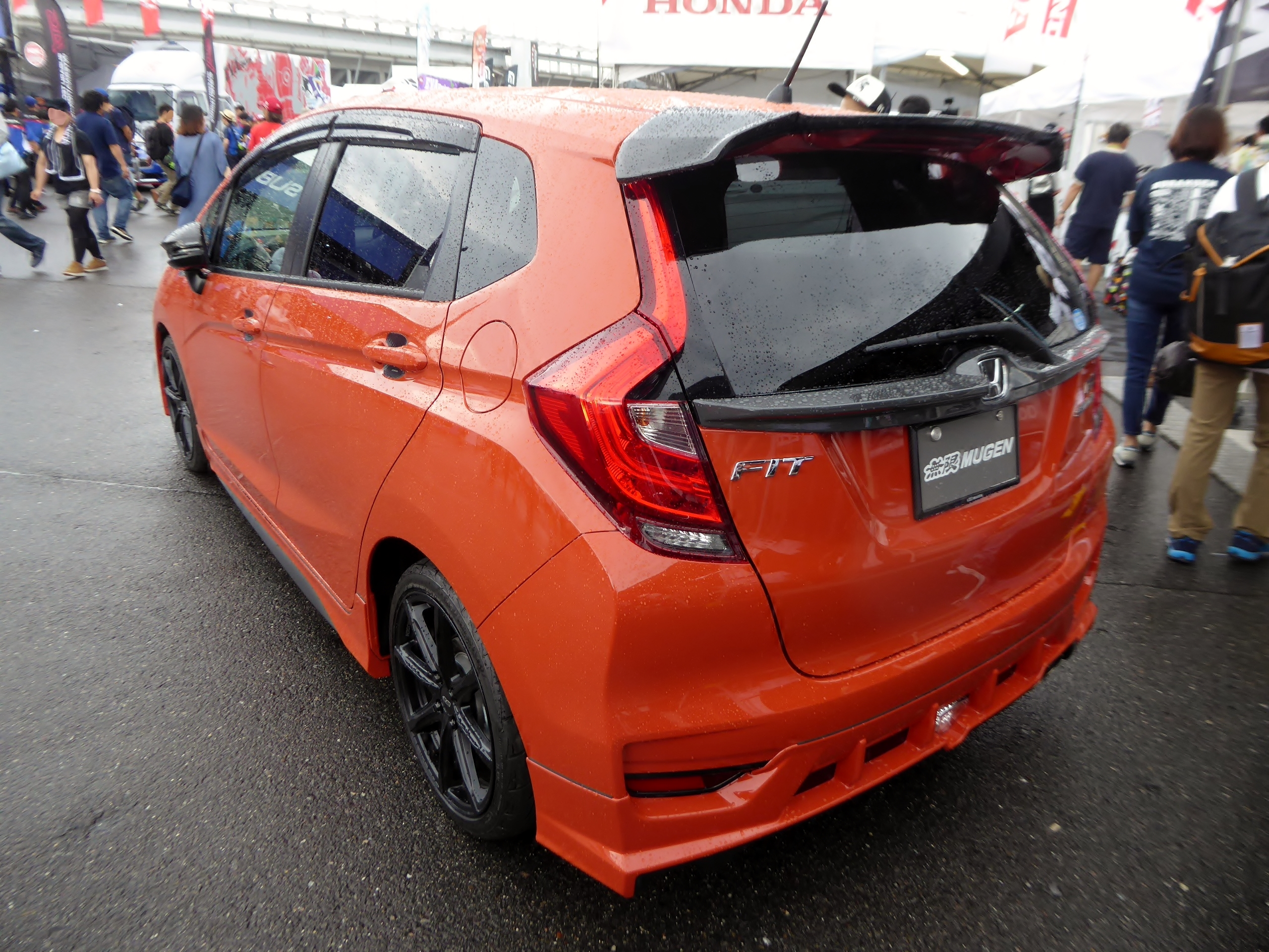 Orange Honda Fit RS with Mugen parts, seen from the rear
